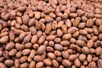 A huge pile of whole pecans partially shelld and most of them in the shell