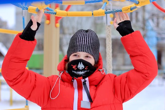 Teenage Girl Wearing Protective Color Fabric Bandana, Mask With A Trendy Skull Print On Her Face, Against Transmissible Infectious Diseases And As Protection From The Weather In The Playground.