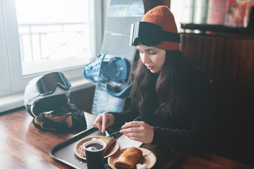Gorgeous female take a food in restaurant on ski resort.