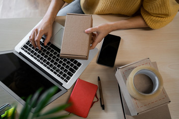 Top view, work place with boxes, laptop. Young small business owner, selling online on a website....