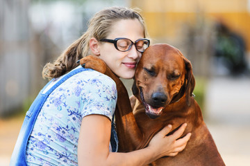 pregnant girl wearing glasses embracing and kissing dog