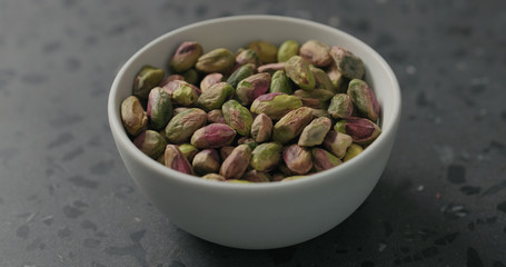 peeled pistachios in white bowl on terrazzo surface