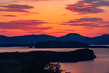 Silhouette of a man sitting on a bench at beautiful sunset. View of the Isle of Skye. Scotland landscape.