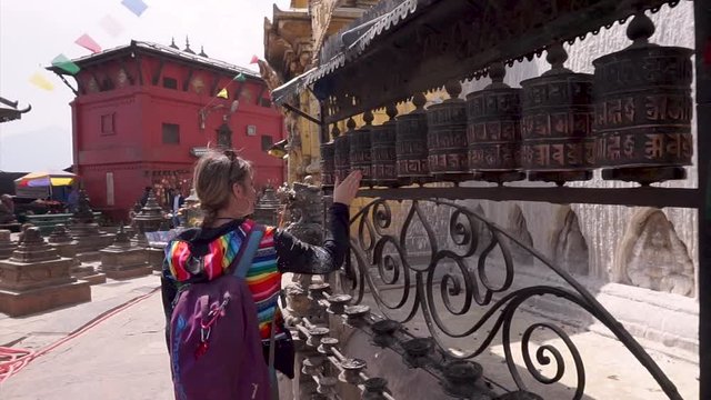 A tourist is rolling prayer wheels at Swayambhunath Stupa (Monkey Temple) in Kathmandu Nepal with the mantra Om Mani Padme Hum