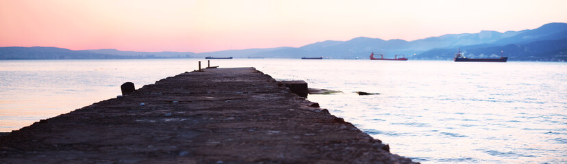 Old pier, sea at sunset. Bay, panoramic view of the bay. Ships on the roadstead