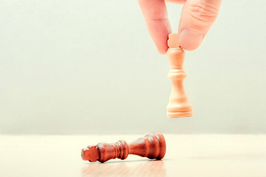 hand puts on the table a white piece of a chess kotol. on the table lies the defeated black king. business success concept..