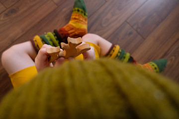 In the village, a little girl in bright colorful knitted socks sits on a wooden floor and plays with wooden toys