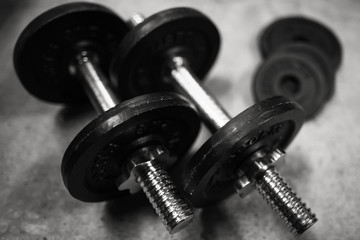 Obraz na płótnie Canvas Fitness or bodybuilding background of old iron dumbbells on grey, conrete floor