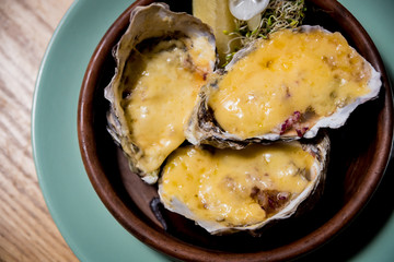 Fresh oysters under cheese on a plate with ice and flowers. Restaurant