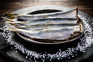 Fresh raw herrings on black stone board on wooden table