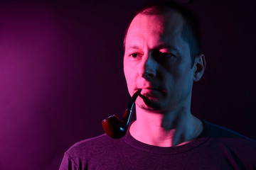 A man smoking tradition pipe. Vibrant colors with neon pink light