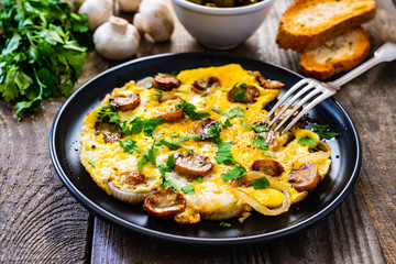 Breakfast - omelette with champignon on wooden background