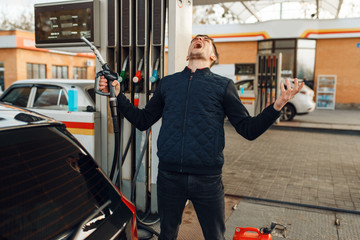 Depressed man cries on gas station, fuel filling