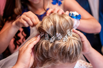 Naklejka premium Bridesmaid helps the bride with her hairstyle