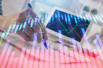Financial forex graph drawn over hands taking notes background. Concept of research. Double exposure