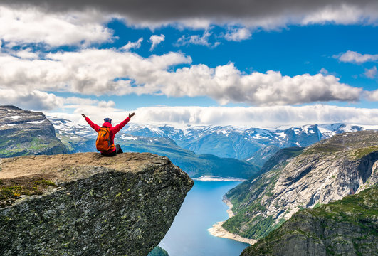Travel concept. Hiker woman sitting on a cliff over a lake, Trolltunga, Norway. Artistic picture. Beauty world. The feeling of complete freedom