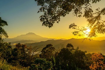 Fototapeta na wymiar The mount Kinabalu with beautiful and golden sunrise, layers of foliages and hills shone by the rising sun.