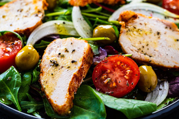 Caesar salad - barbecue chicken breast and vegetables on wooden table