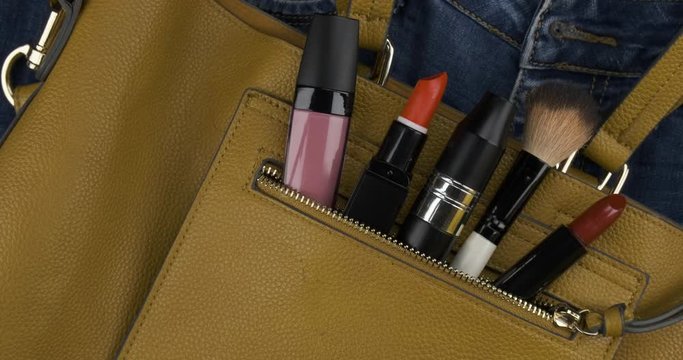 Rotation. Cosmetics sticks out of the open pocket of a woman's bag.
