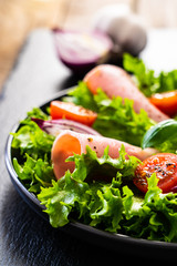 Tasty salad - ham and vegetables on black stone board