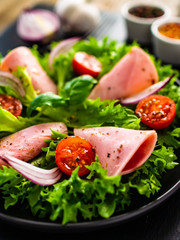 Tasty salad - ham and vegetables on black stone board