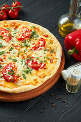 Oven-baked pizza margherita with tomatoes, mozzarella cheese and red sauce on a wooden background in a composition with ingredients. Close up view on food flat lay