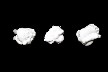 Collection of various strokes of shaving cream on black background