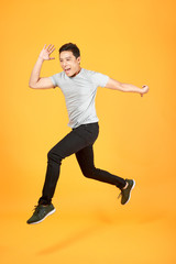Fototapeta na wymiar Handsome jumping Asian man on color background