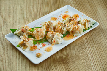 Traditional Chinese cuisine - Dim Sum with chicken, pork or seafood on a white ceramic plate with sweet and sour sauce on wooden background. Close up view