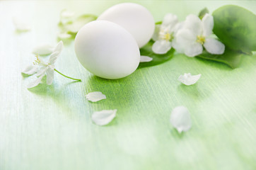 Fototapeta na wymiar Apple trees flowers and green leaves. Chicken white eggs on wooden table background. Easter and spring.