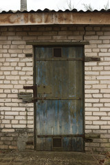 old blue, miserable shabby door on a brick white wall