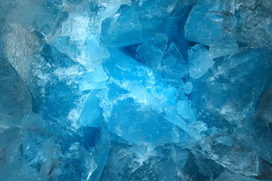 Pieces of crushed blue ice glass cracks background texture. close-up frozen water
