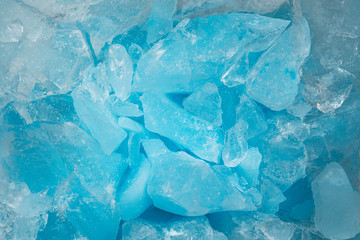 Pieces of crushed blue ice glass cracks background texture. close-up frozen water