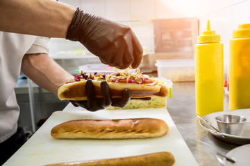 The chef cooking hot dog on a grill. Restaurant.