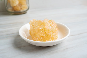 A dish of yellow rock sugar on the kitchen tile countertop