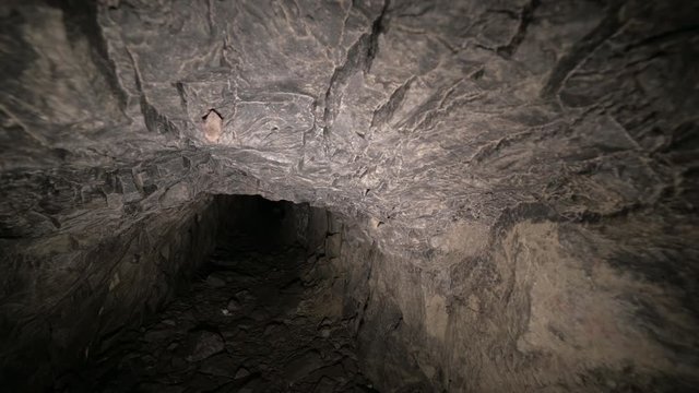 Flashlight illuminates dark passage in cave. Graffiti. Old abandoned mine.