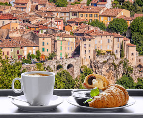 Coffee with croissants against Moustiers Sainte Marie village in Provence, France