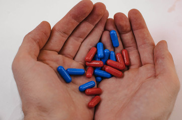 heap of capsule tablets of red and blue in the hands of a man