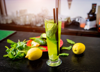 Non alcoholic cocktail with lime and mint at wooden bar counter.