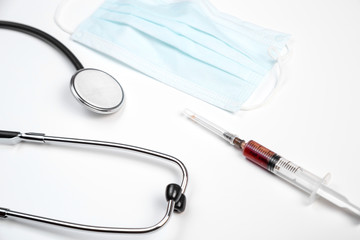 medical stethoscope, disposable mask and syringe with blood samples on a white isolated background