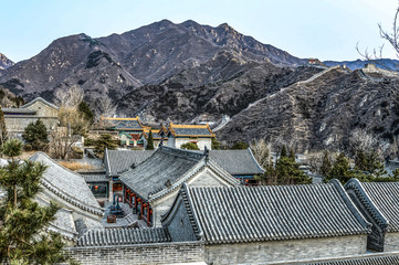 Buildings of a tourist city naer a fragment of the Great Chinese Wall in the mountains near Bejing