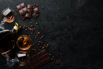 Brandy and chocolate on a black stone table. Top view. Free space for your text.