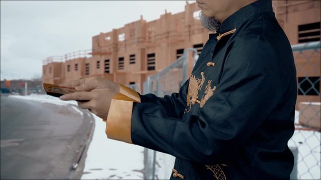 Feng Shui Master checks the Lo-Pan compass to be sure that nature's energy force is in harmony with a housing construction project - winter