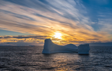 Goergeous sunset over giant icebergs and stunning polar landscapes along the coast of the Antarctic Peninsula