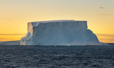 Goergeous sunset over giant icebergs and stunning polar landscapes along the coast of the Antarctic...