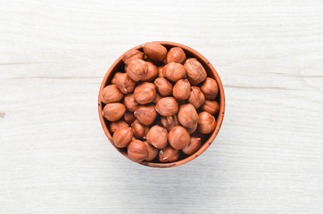 Hazelnuts in bowl on white wooden background. Nut.