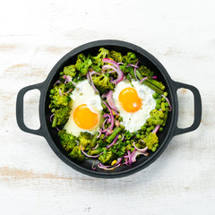 Vegetable Shakshuka in a pan. Fried eggs with vegetables: broccoli, green peas, beans, onions. Top view. Free space for your text.