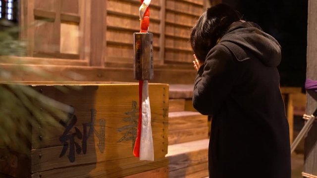 Japanese girl praying at shrine during typical new year tradition
