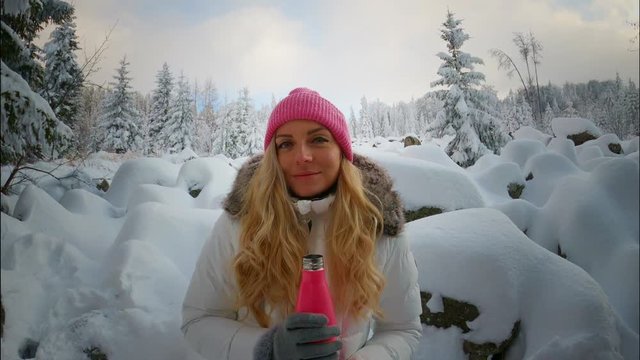 Seductive woman drinking water in forest covered by snow during winter, Europe
