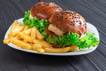 tasty appetizing burgers on a white terrel with fries on a gray background